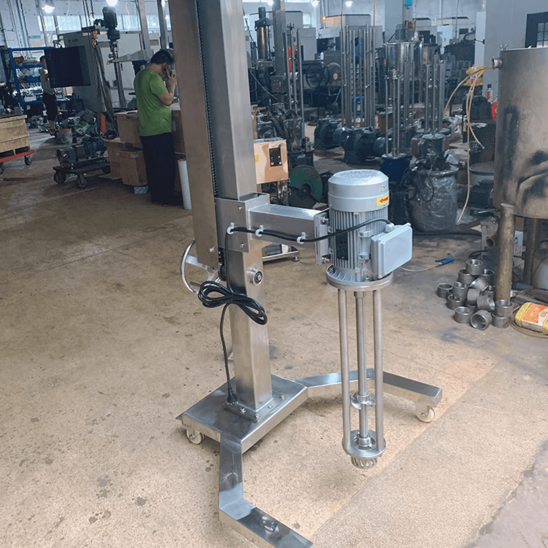 Industrial stainless steel high-shear mixer on a mobile wheeled stand inside a manufacturing facility.
